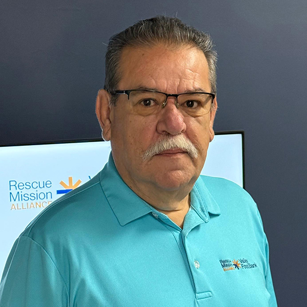 Rescue Mission Alliance staff member in a blue polo shirt at the organization office.