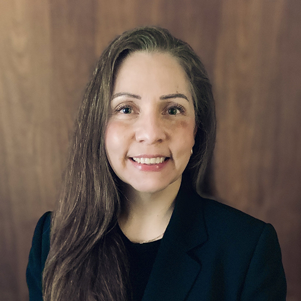 Rescue Mission Alliance staff member smiling in professional attire against wooden background.