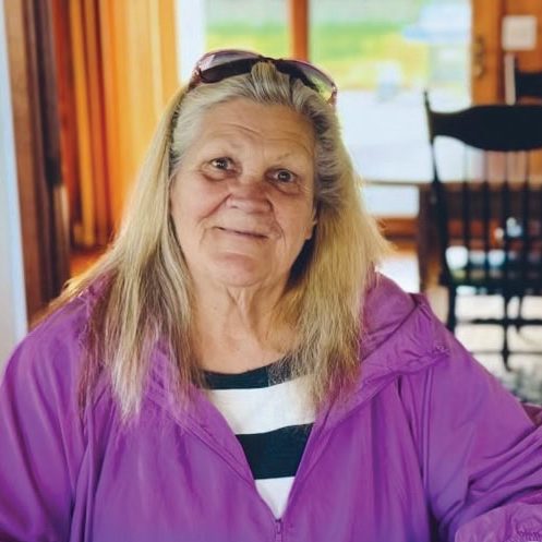 Helping woman at Rescue Mission Alliance, smiling, indoor setting, community support, volunteer work.